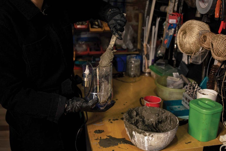 O persoană umple un amestec de beton într-un recipient transparent pentru a realiza un proiect DIY.