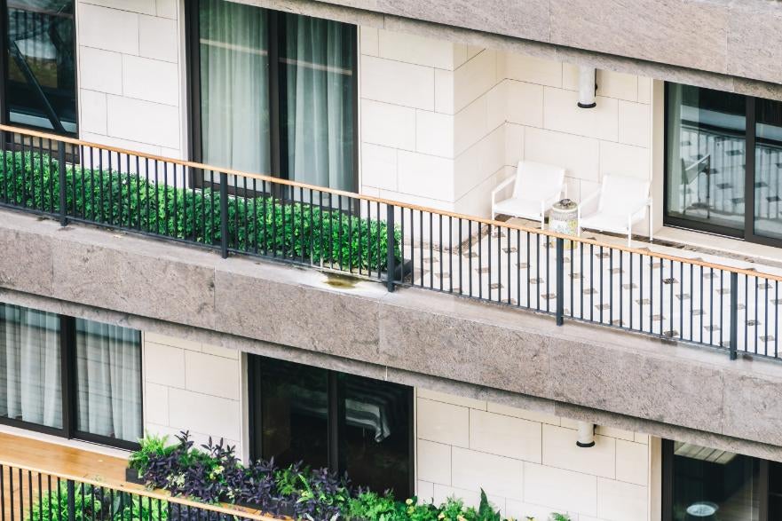 Exteriorul unei clădiri cu balcoane decorate cu plante, scaune și mese.