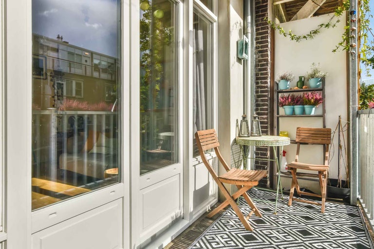 Balcon decorat cu zonă de relaxare din lemn și raft pentru plante