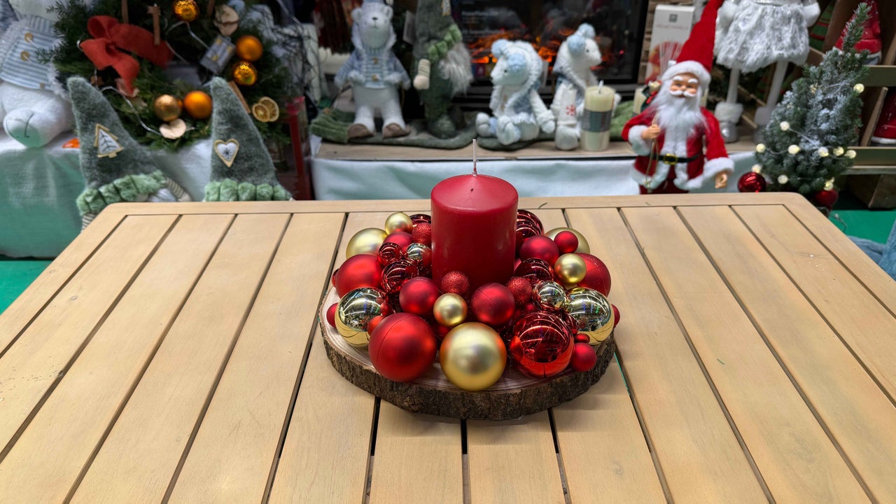 Decorație cu lumânare roșie și globuri de Crăciun pe masă de lemn