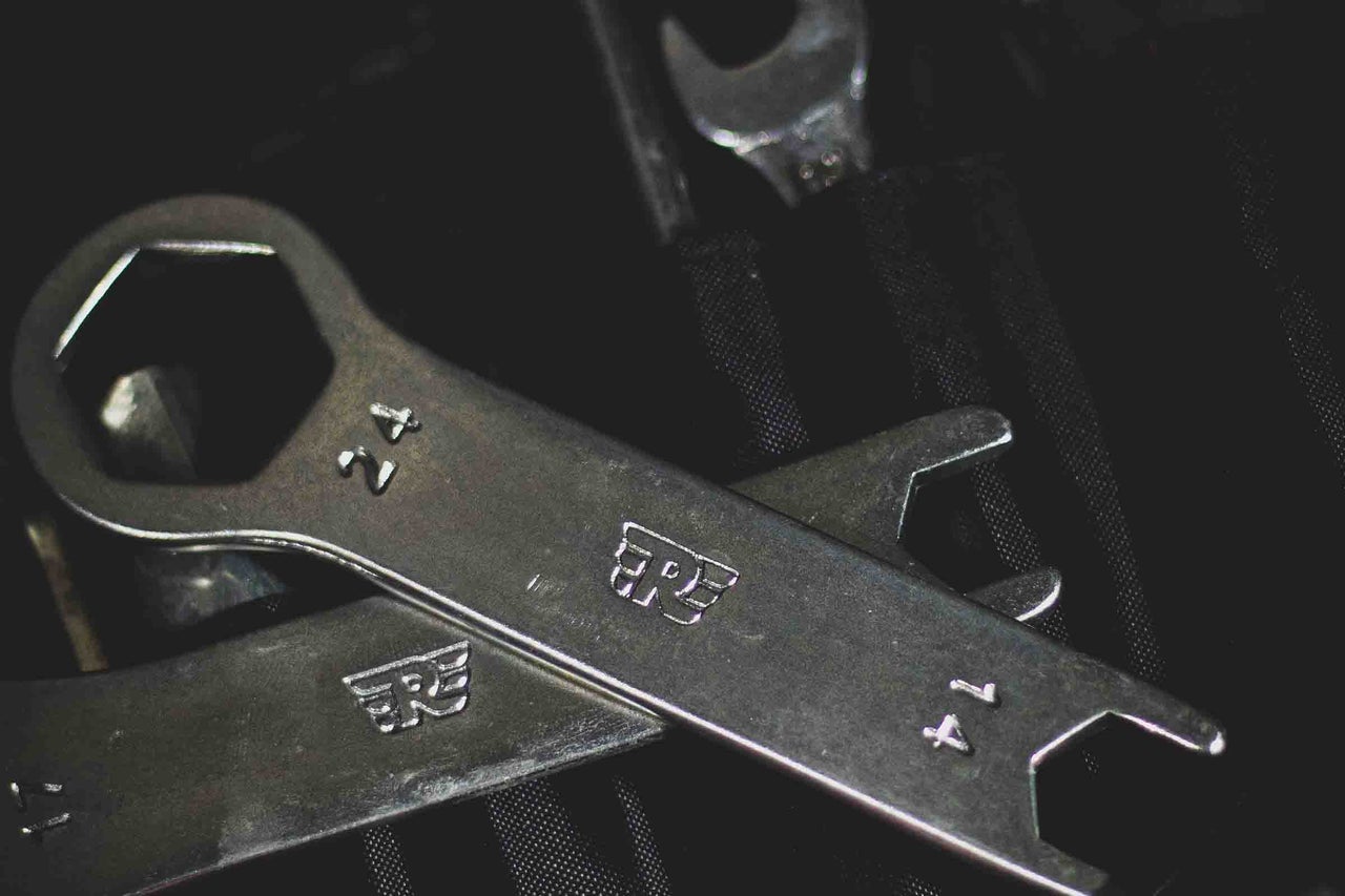 Cheie inelară de mărimea 24 și cheie fixă de mărimea 14 din metal pe o geantă de unelte.