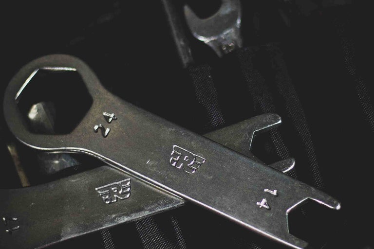 Cheie inelară de mărimea 24 și cheie fixă de mărimea 14 din metal pe o geantă de unelte.