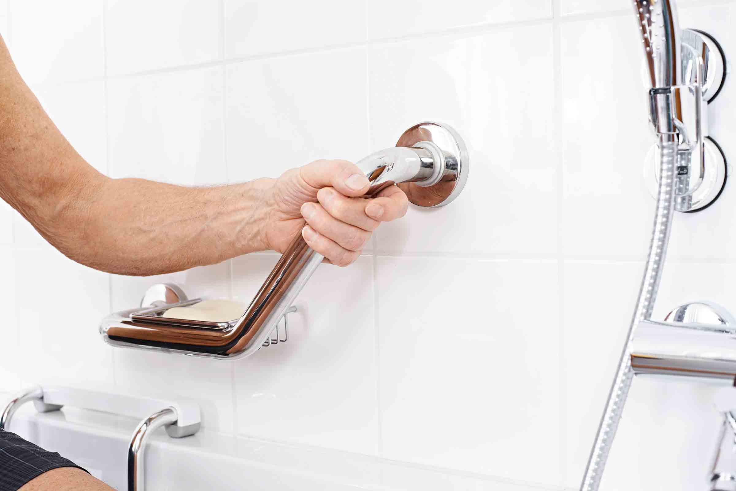 O persoană folosește un bară de sprijin cu săpunieră în baie