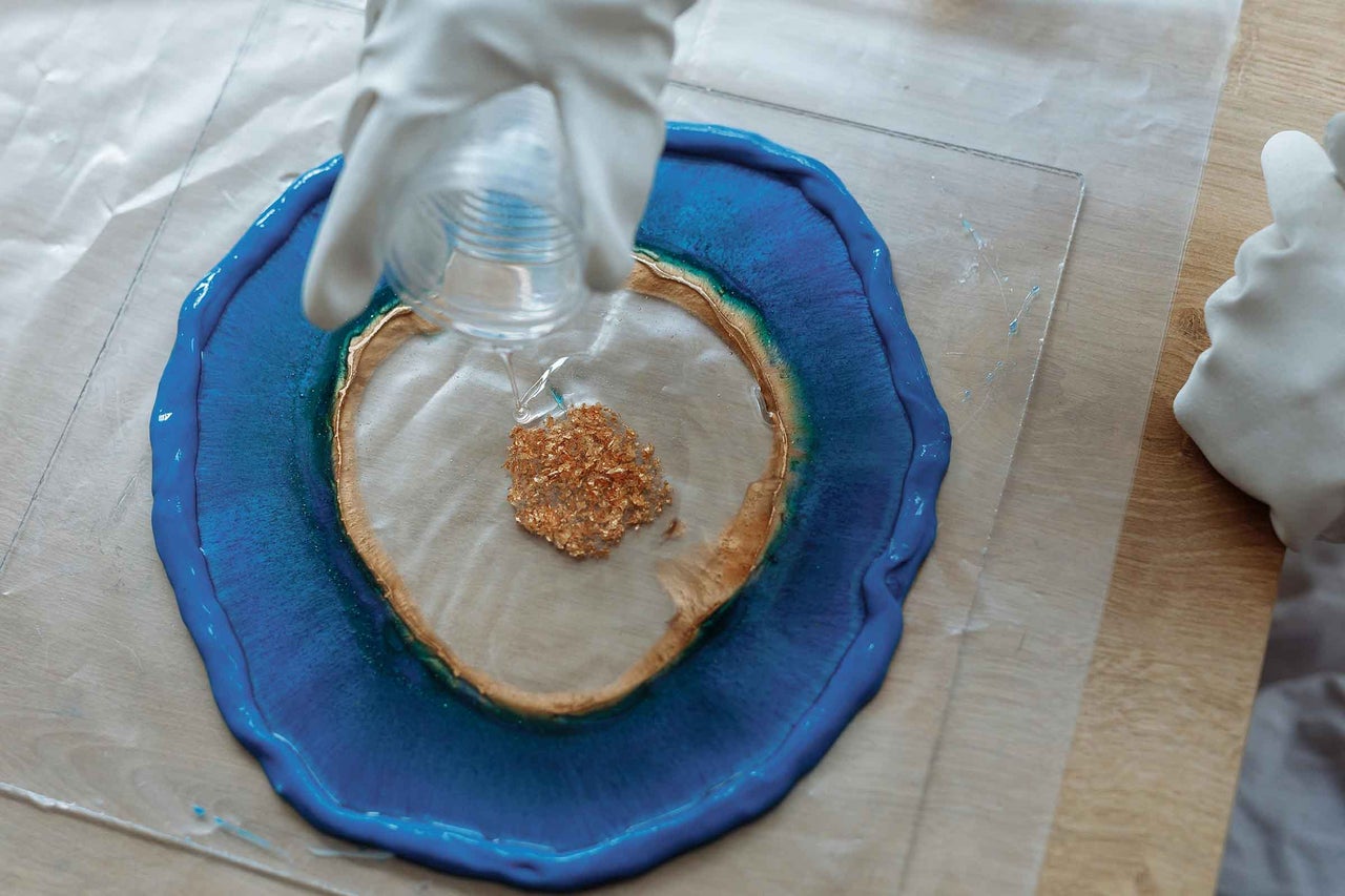 Rășină de turnare turnată într-o formă cu margine albastră cu fulgi de aur.