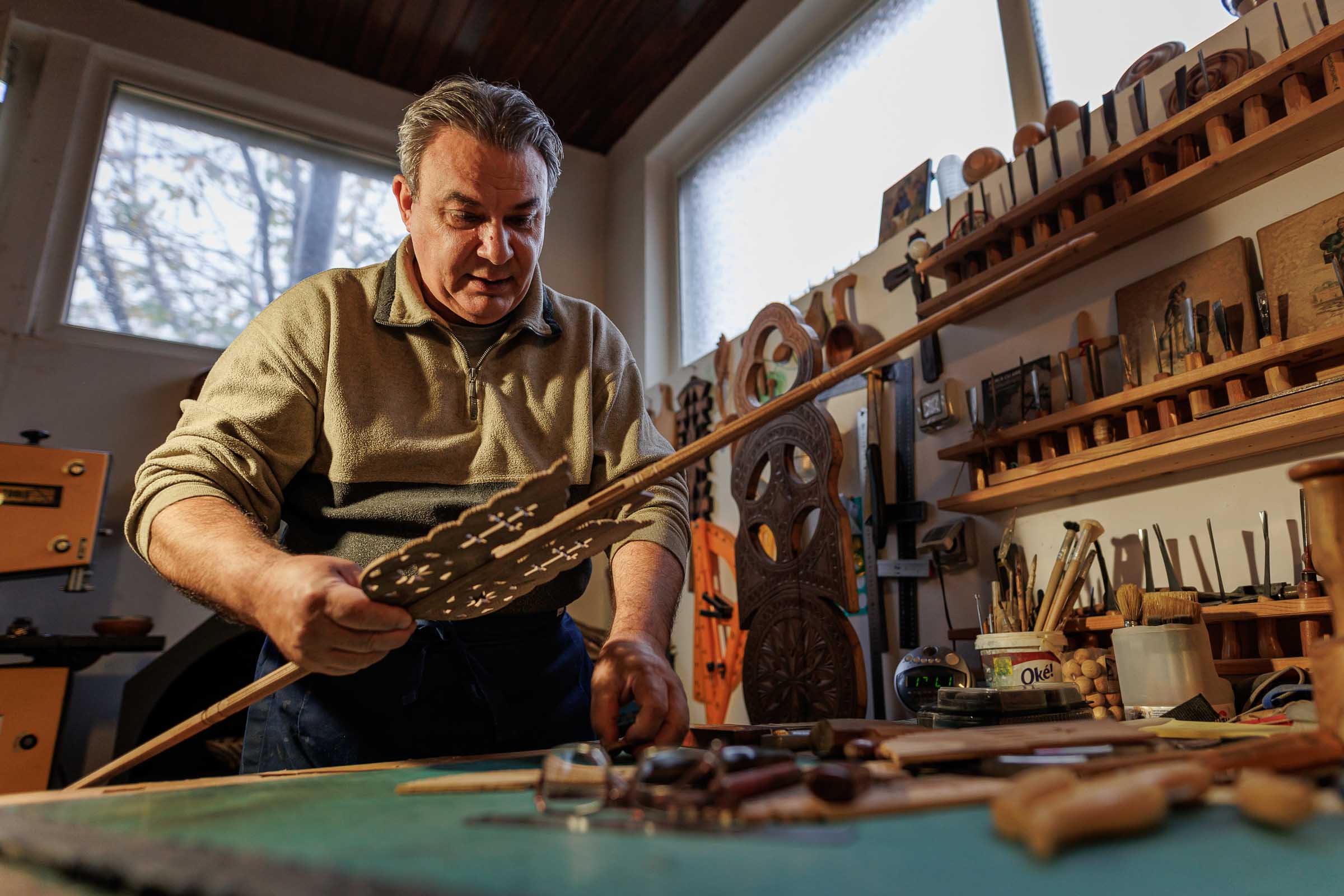 Artizan care lucrează o piesă de lemn sculptată în atelierul său.