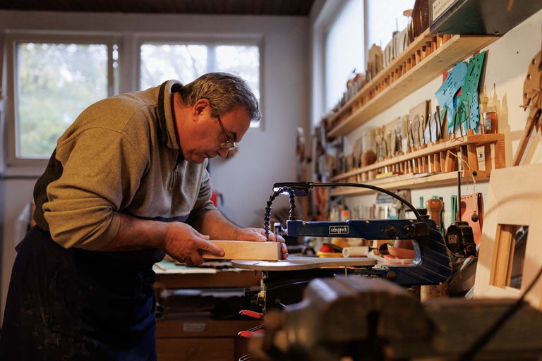 Un bărbat lucrează cu un ferăstrău de traforaj Scheppach într-un atelier.