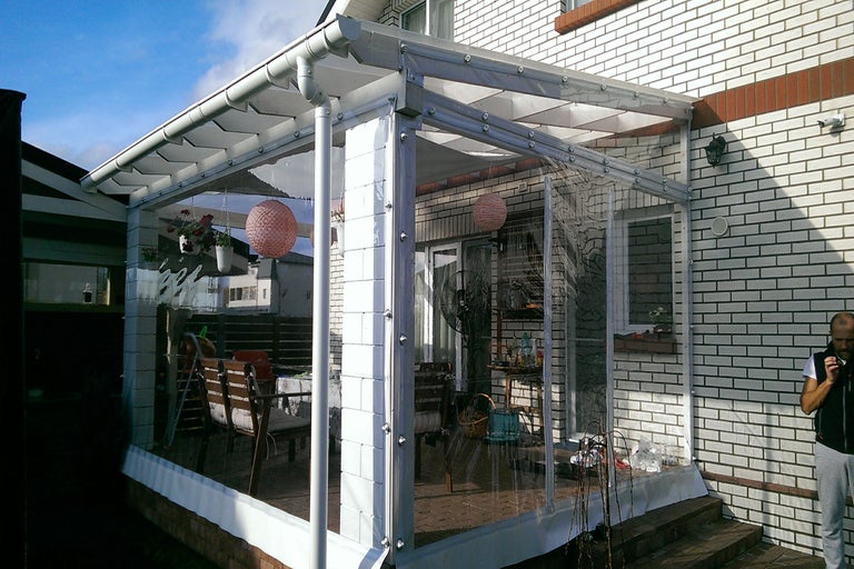 Terasa acoperită cu pereți laterali transparenți și cadru alb