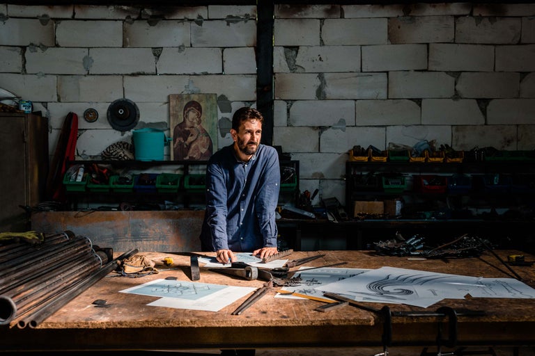 Atelier cu bărbat, unelte și desene pe o masă