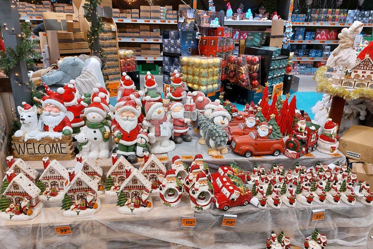 Figurine și case decorative de Crăciun expuse pe un raft într-un magazin de bricolaj.