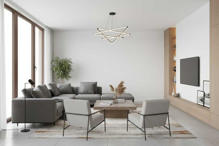 Living luminos cu canapea de colț gri, două fotolii, măsuță de cafea și lampă modernă de plafon