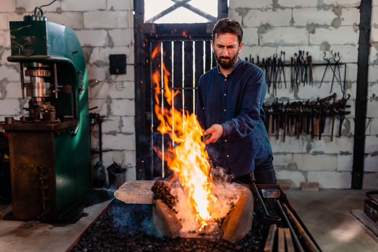 Fierar care lucrează la cuptorul de forjă într-un atelier