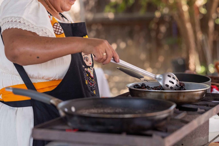 Femeie gătește cu ustensile de gătit în tigăi pe o sobă