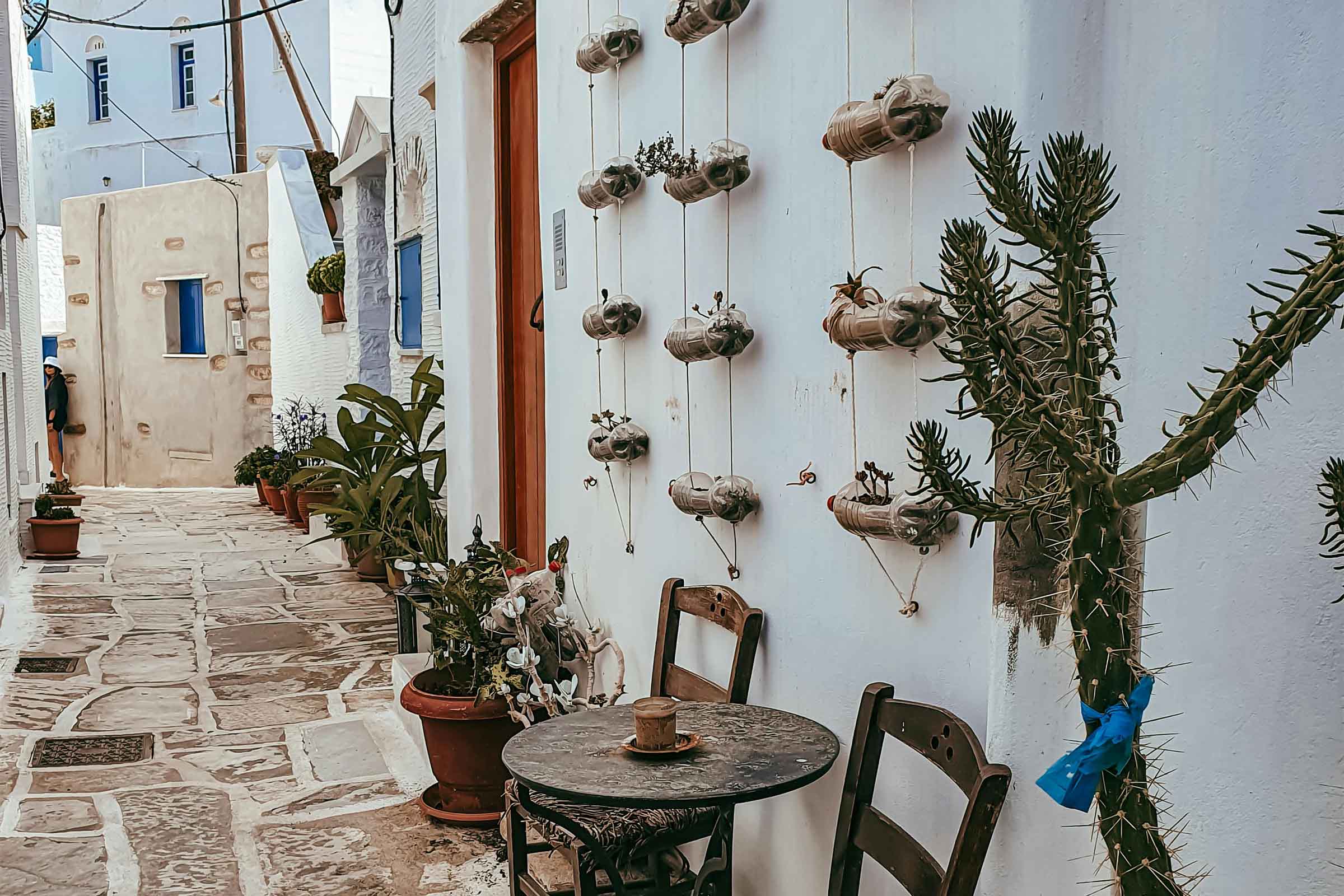 Scenă stradală decorativă cu masă, scaune, cactus și jardiniere suspendate