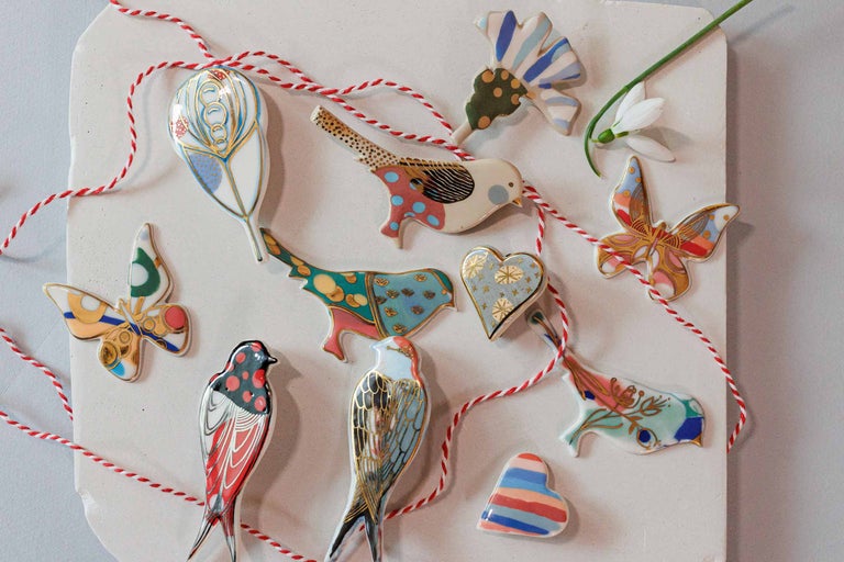 Figurine decorative cu motive de păsări, fluturi și inimă, precum și un cordon roșu și alb pe o suprafață