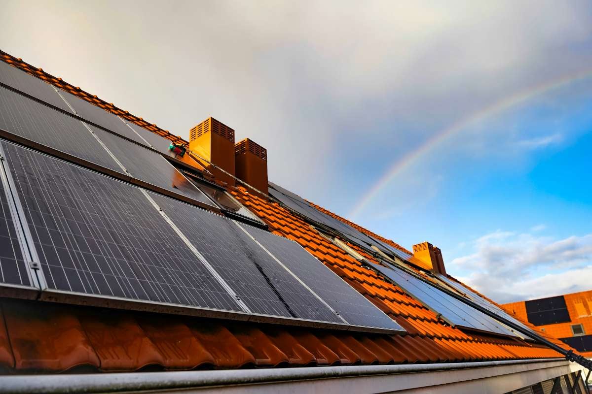 Sistem solar pe acoperișul unei case cu țigle și coșuri de fum.