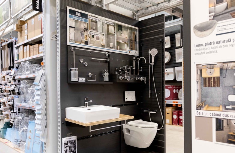 Expoziție de baie cu lavoar, toaletă și robinete pe fundal închis