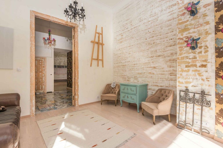 Cameră de zi luminoasă cu mobilier vintage, decorațiuni și trecere deschisă spre o altă cameră