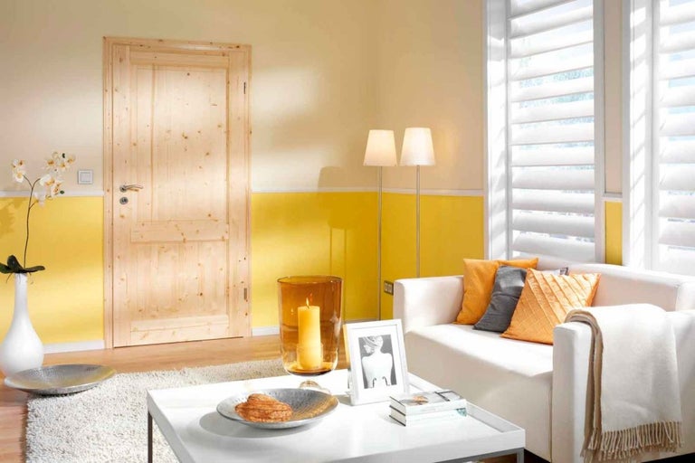 Spațiu de locuit luminos cu ușă din lemn, canapea, masă și jaluzele