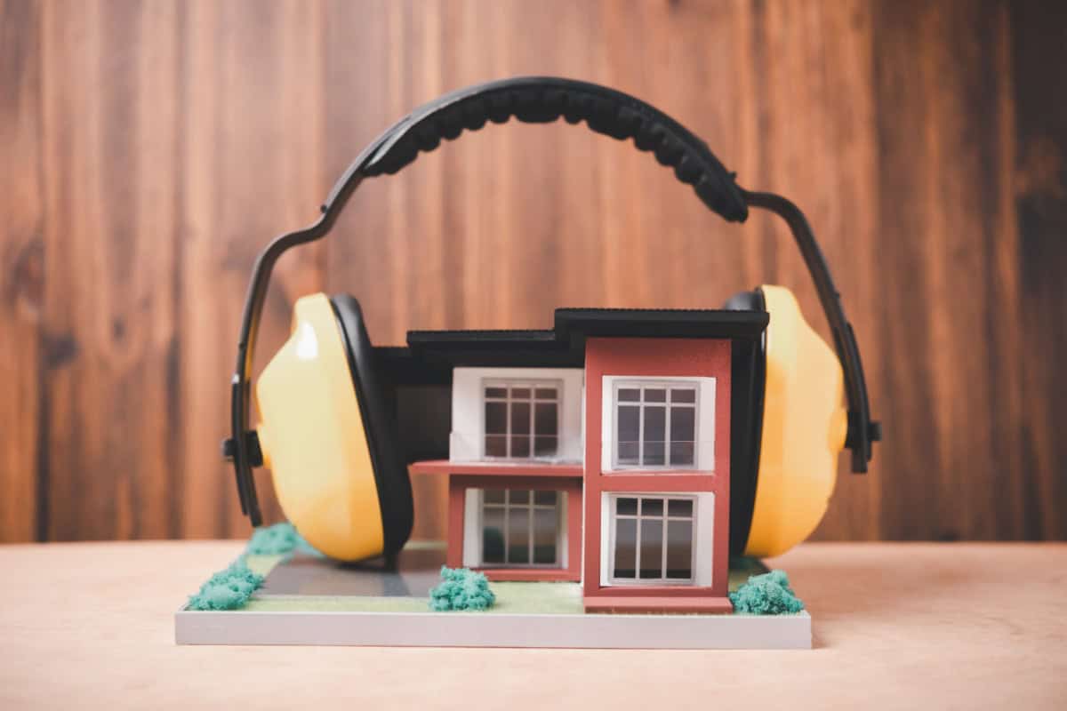 Scenă cu un model de casă și căști care reprezintă protecția împotriva zgomotului