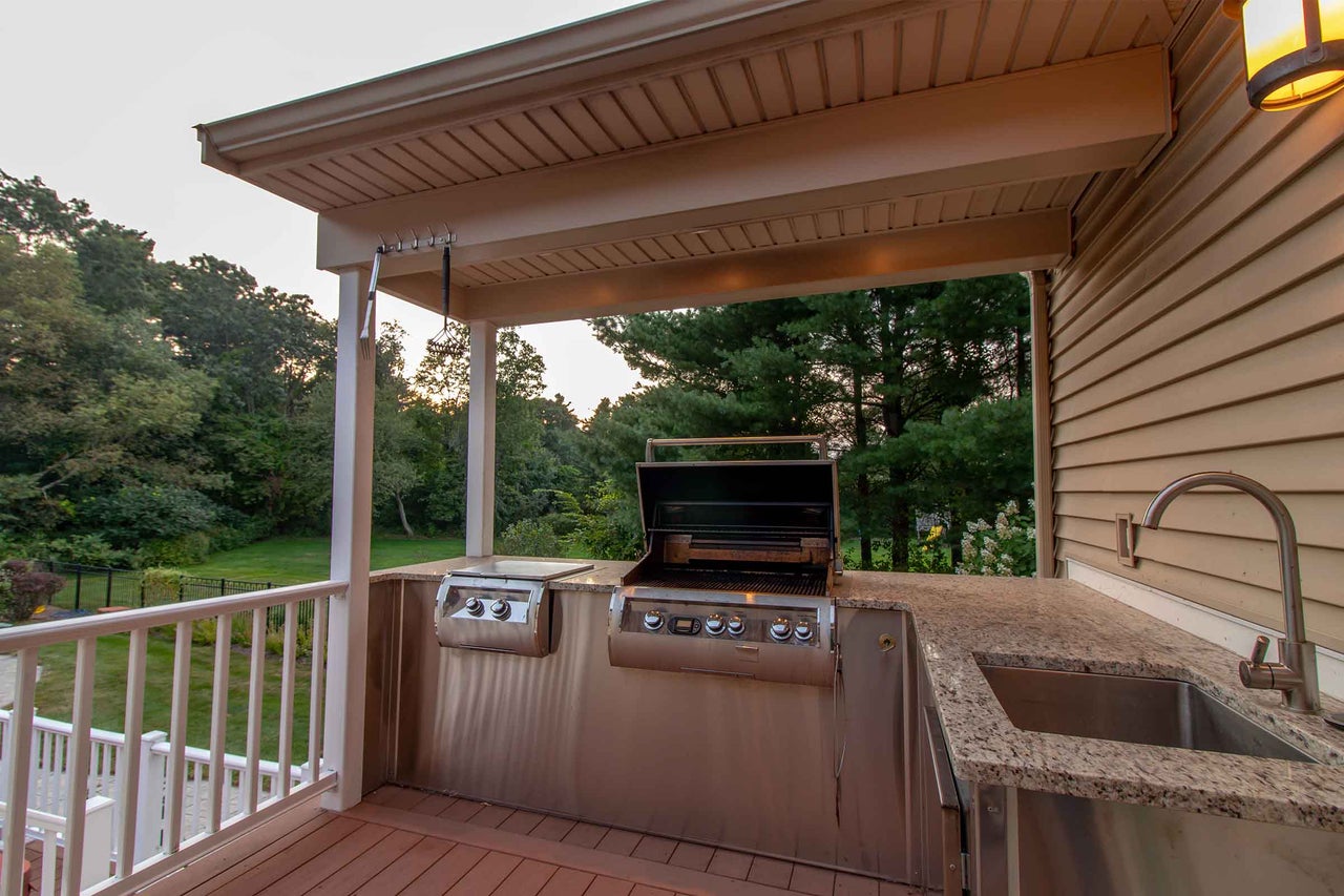 Bucătărie exterioară cu grătar, chiuvetă și blat de lucru pe o terasă