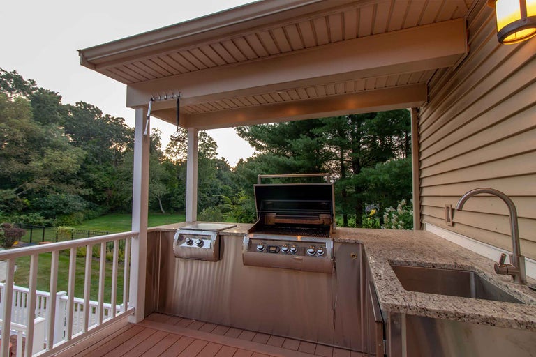 Bucătărie exterioară cu grătar, chiuvetă și blat de lucru pe o terasă