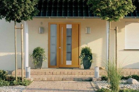 Ușă de intrare cu panou lateral, inserții de sticlă și design simplu în fața unei case de locuit.