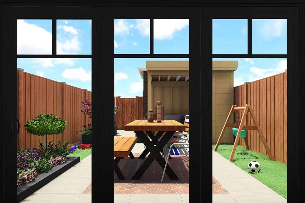 Vedere prin uși negre de terasă spre o grădină luminoasă cu masă din lemn, bancă, magazie de grădină, gard din lemn, straturi de flori și leagăn.