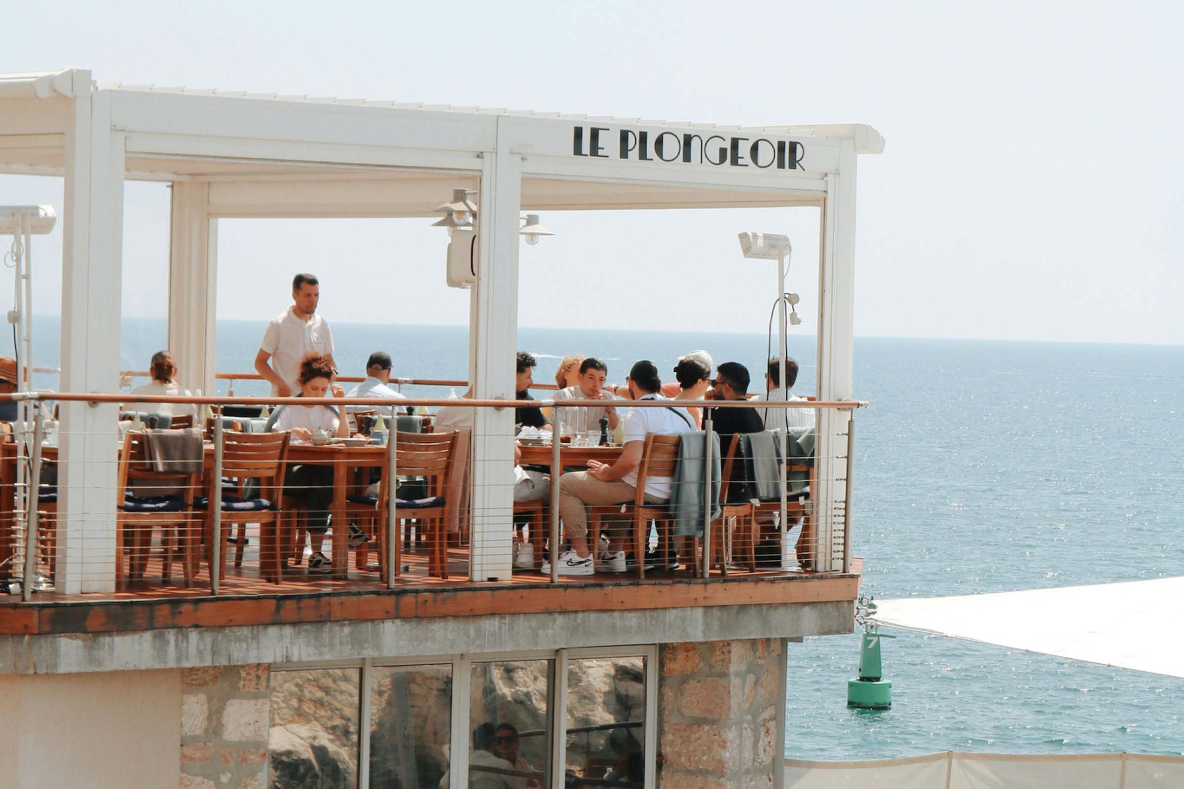 Terasa de restaurant cu vedere la mare și oaspeți la mese