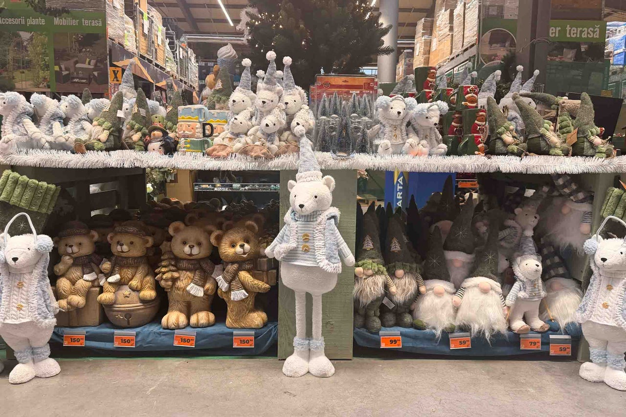 Decoratiuni de Craciun intr-un magazin de bricolaj cu ursuleti de plus, figurine spiridusi si accesorii decorative pe rafturile de vanzare.