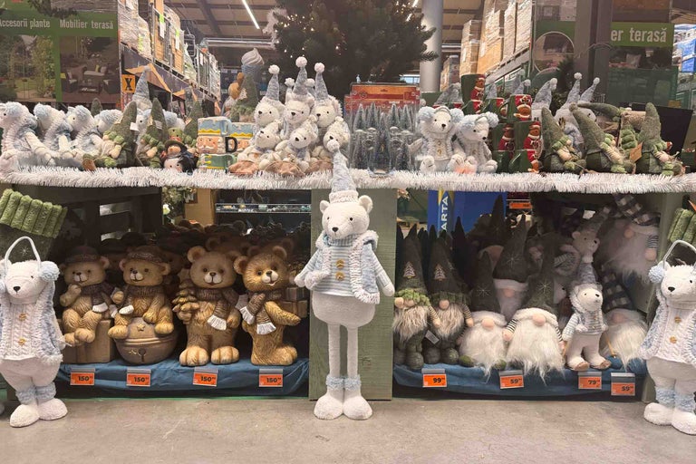 Decoratiuni de Craciun intr-un magazin de bricolaj cu ursuleti de plus, figurine spiridusi si accesorii decorative pe rafturile de vanzare.