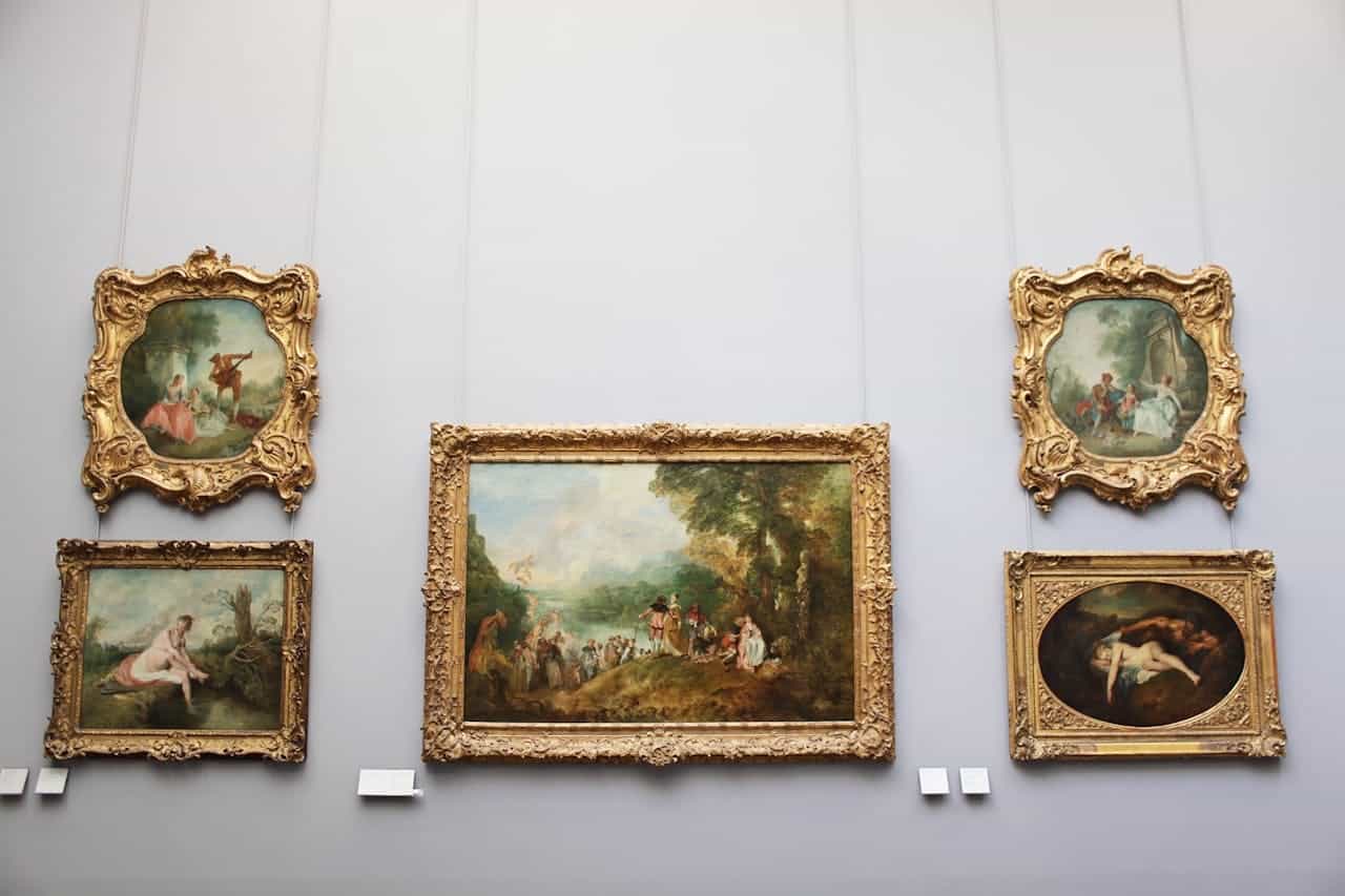 Cinci tablouri înrămate atârnă pe un perete și prezintă diverse scene și figuri.