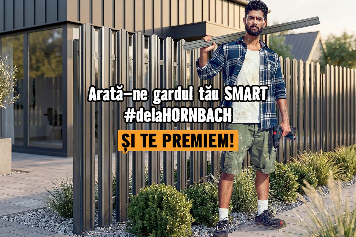 Un bărbat în haine de lucru ține un element de gard lângă un gard metalic modern în fața unei case.