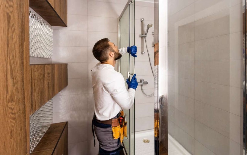 Instalator instalează o cabină de duș în baie.