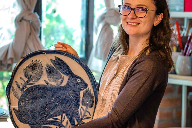 Femeie ținând o farfurie decorativă din ceramică cu motiv de iepure