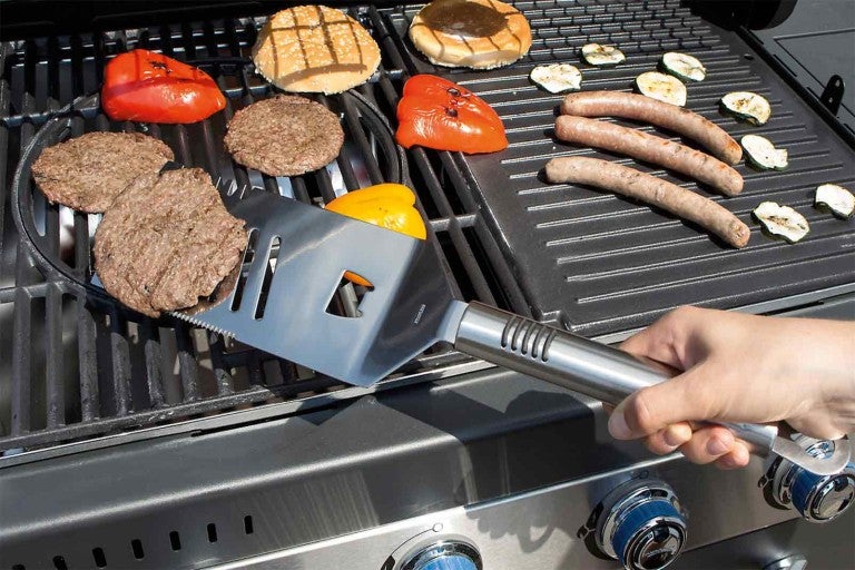 Scenă la grătar cu hamburger, ardei gras, cârnați, dovlecel și spatulă pentru grătar pe un grătar