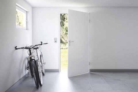 Cameră luminoasă cu biciclete și ușă interioară deschisă