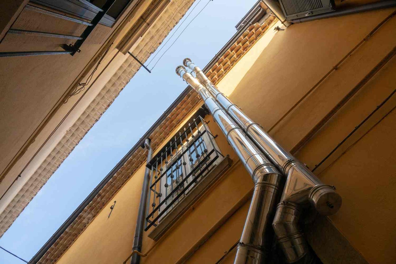 Privire de jos în sus asupra a două coșuri de fum din oțel inoxidabil pe un perete al casei