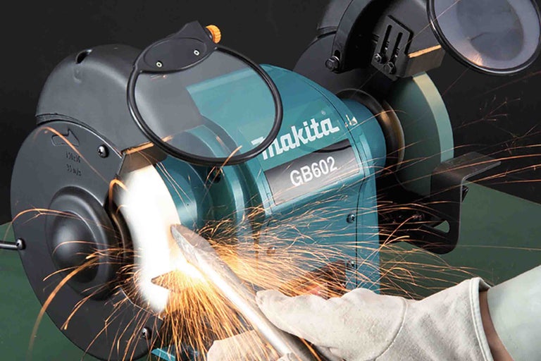 Polizor dublu Makita GB602 șlefuind o bucată de metal cu scântei