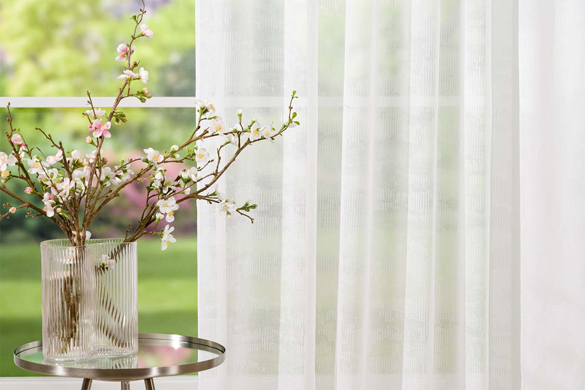 Scenă decorativă cu perdea, masă și flori într-o vază