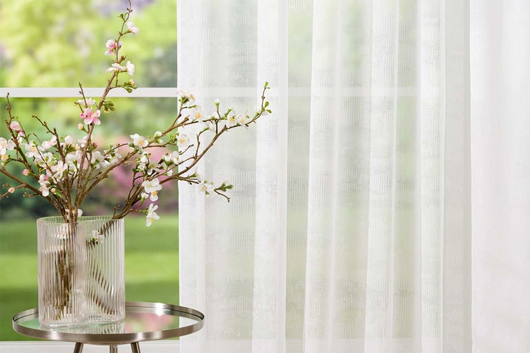 Scenă decorativă cu perdea, masă și flori într-o vază