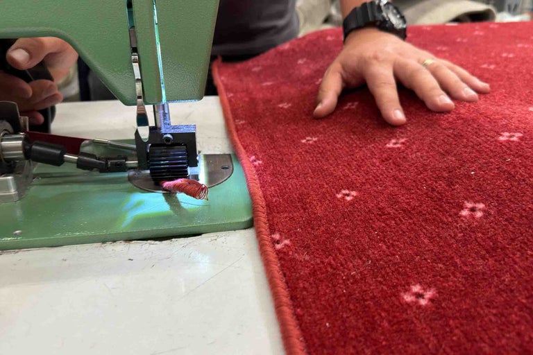 Mașină de bordurat covoare care tiveste un covor roșu