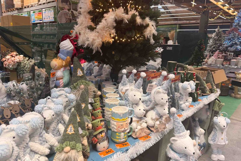 Decorațiuni de Crăciun și căni cu motive de iarnă pe o masă de vânzare într-un magazin de bricolaj