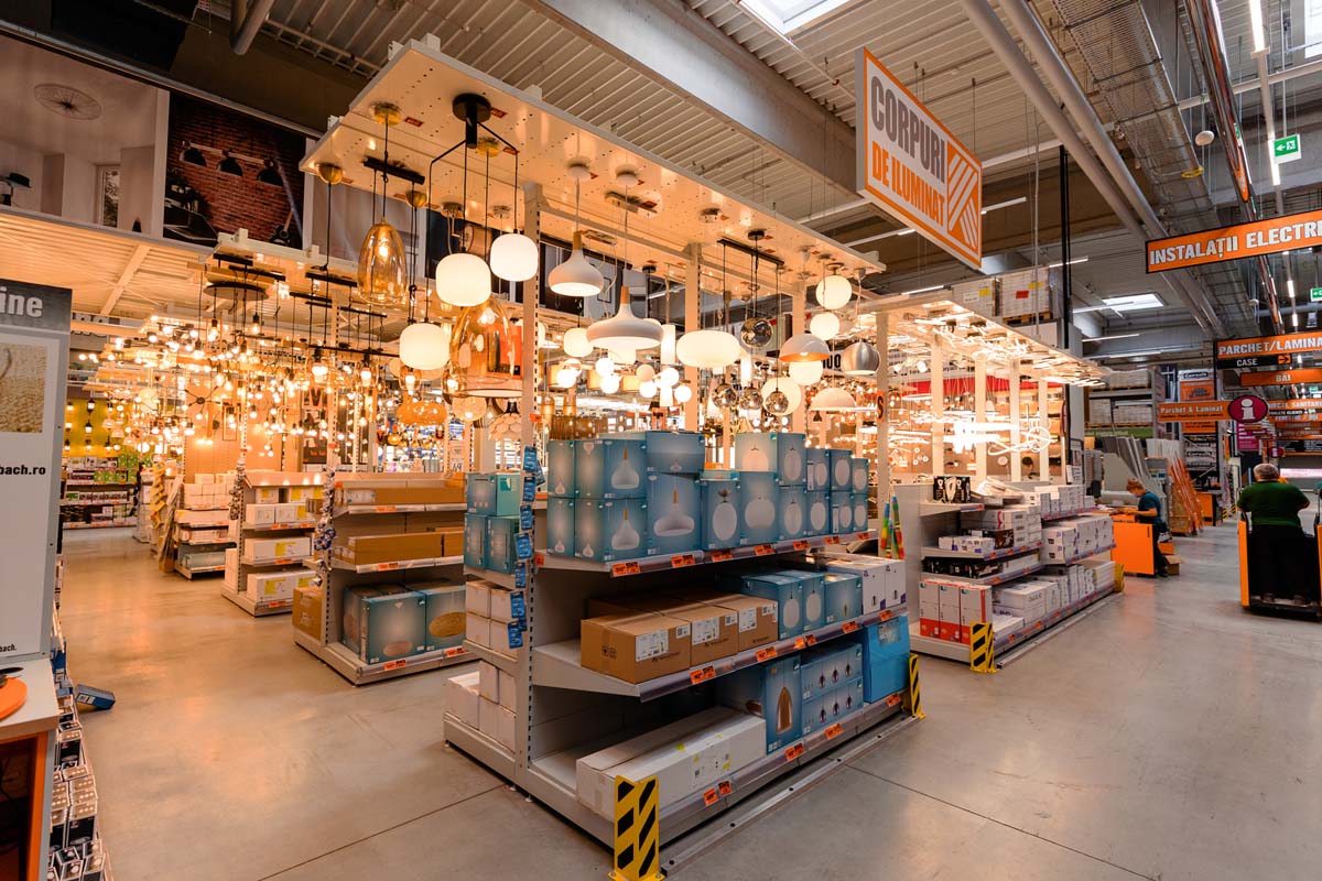 Vedere a secțiunii de iluminat dintr-un magazin Hornbach, cu diverse lămpi și corpuri de iluminat pe rafturi și pe tavan