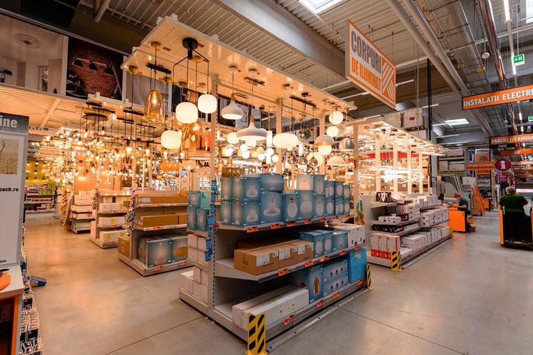 Vedere a secțiunii de iluminat dintr-un magazin Hornbach, cu diverse lămpi și corpuri de iluminat pe rafturi și pe tavan
