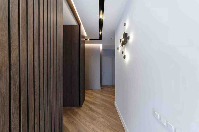 Hol modern cu panouri de perete din lamele de lemn, parchet cu aspect de lemn și aplică decorativă.