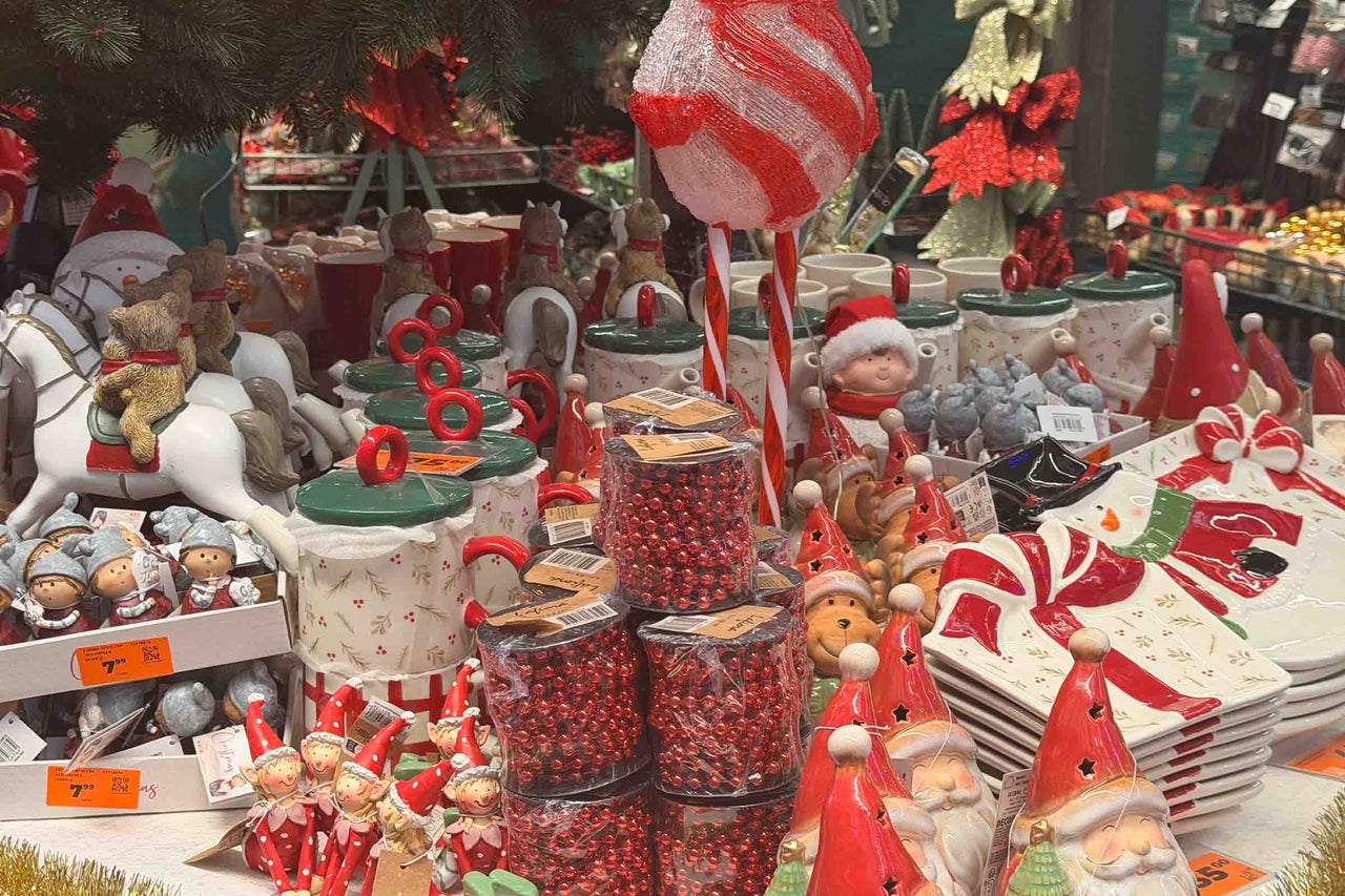 O selecție de decorațiuni de Crăciun și veselă cu figurine Moș Crăciun, elfi, borcane decorative și șiraguri de mărgele strălucitoare.