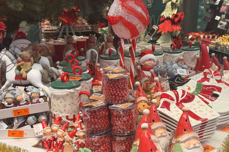 O selecție de decorațiuni de Crăciun și veselă cu figurine Moș Crăciun, elfi, borcane decorative și șiraguri de mărgele strălucitoare.