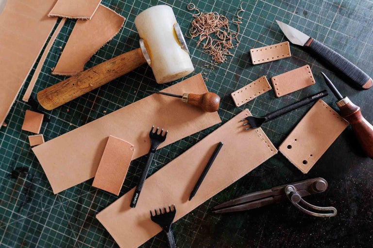 Unelte de prelucrare a pielii și bucăți de piele pe o placă de tăiat