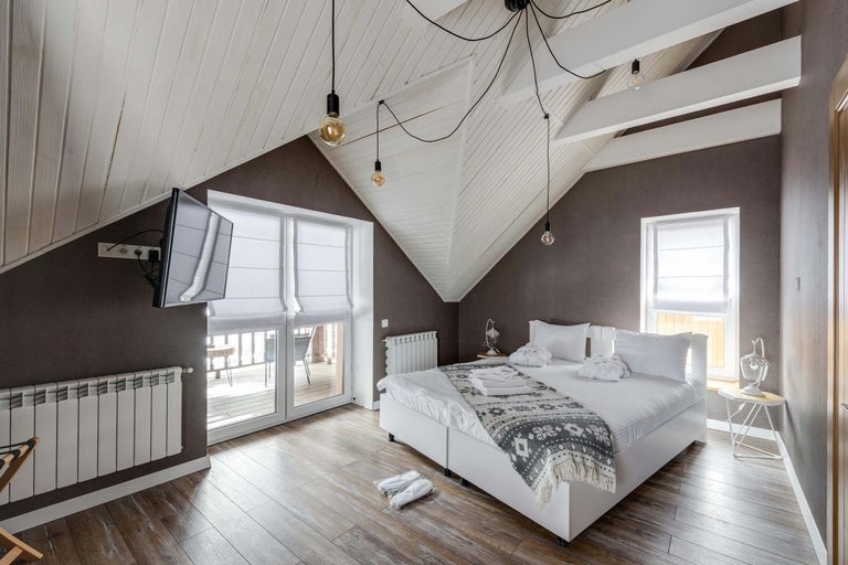 Dormitor luminos cu tavan înclinat, pat dublu, radiator și televizor