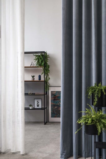 Scenă de cameră cu perdele albe și gri și un raft cu plante de apartament